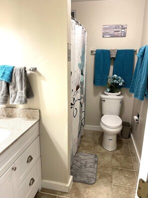 Een badkamer met toilet, douchegordijn en een handdoekrek met meerdere handdoeken.