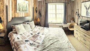 A bedroom with a bed, a TV, a dresser, and a window with curtains. - 1st FL Mtn View Woodland Suite on Jiminy Sleeps 4 Ski On/Off, Fully Redone Count (Hancock)