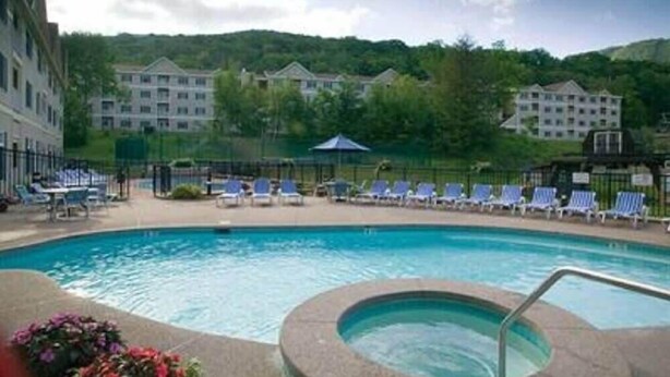 A swimming pool with lounge chairs and a hot tub, surrounded by buildings and greenery. - 1st FL Mtn View Woodland Suite on Jiminy Sleeps 4 Ski On/Off, Fully Redone Count (Hancock)