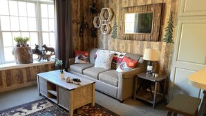 A cozy living room with a sofa, coffee table, and a rug. - 1st FL Mtn View Woodland Suite on Jiminy Sleeps 4 Ski On/Off, Fully Redone Count (Hancock)