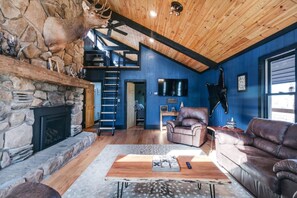 A rustic interior with a stone fireplace, leather furniture, a wooden ceiling, and a mounted animal head. - Cozy Mountain Cabin, dark skies, and great views! (West Branch Township)