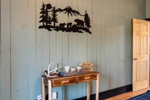 A wooden table with antlers and a bear sculpture against a wall with a wildlife silhouette. - Cozy Mountain Cabin, dark skies, and great views! (West Branch Township)