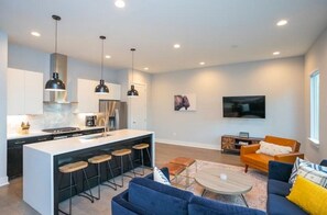 Relax in this stylish living space with a central island, comfortable seating area, and modern kitchen.