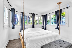 A bedroom with a bed, a bench, and a view of greenery through large windows. - 4100 sq feet Unique Hollywood Hills view home (Los Angeles)