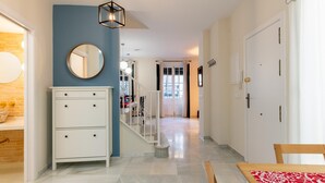 A hallway with a white cabinet, a round mirror, and a geometric pendant light. - Holi-Rent Peñuelas (Sevilla)