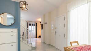 A modern interior with a staircase, a dining area with a table, and a white dresser. - Holi-Rent Peñuelas (Sevilla)