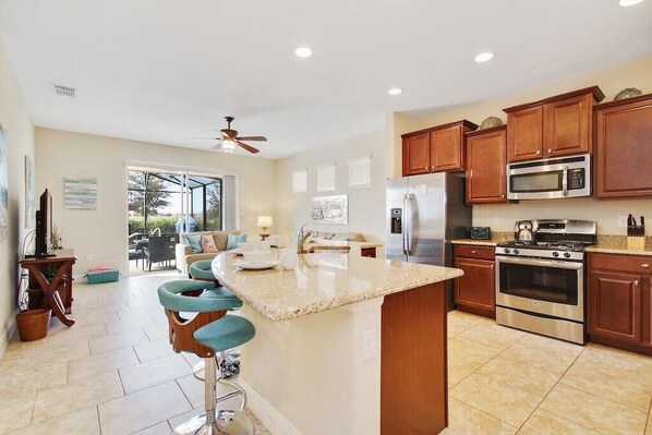 A spacious kitchen with a central island, stainless steel appliances, and wooden cabinets. - New Listing - Kiwi’s Retreat, Disney Vacation Home in Solterra Resort (Davenport)
