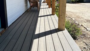 A wooden deck with a covered porch, a wicker chair, and a small table. - Bear Lake Sleeps 44 Private Inn  Family Reunions Groups (Paris)