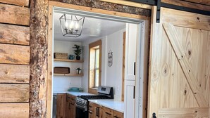A rustic kitchen with wooden cabinets, a stove, and a dining area with a table and chairs. - Bear Lake Sleeps 44 Private Inn  Family Reunions Groups (Paris)
