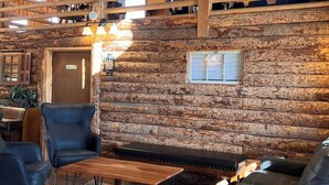 A cozy interior with a stone wall, wooden beams, a sofa, a table, and a bench. - Bear Lake Sleeps 44 Private Inn  Family Reunions Groups (Paris)