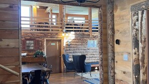 A rustic wooden interior with a dining area, a staircase, and a view of a balcony. - Bear Lake Sleeps 44 Private Inn  Family Reunions Groups (Paris)