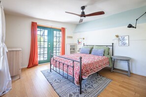 A bedroom with a bed, a ceiling fan, a window with curtains, a bedside table, and a rug.