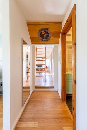 Un pasillo con suelo y techo de madera, y una puerta que da a una habitación con cocina.