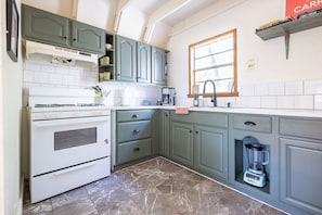 Una cocina con estufa, horno, lavabo y una licuadora integrada.