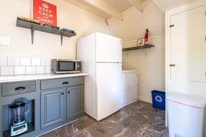 Una cocina compacta con microondas, refrigerador y licuadora sobre la encimera.