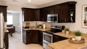 Une cuisine moderne avec des meubles en bois foncé, des appareils électroménagers en acier inoxydable et un plan de travail en granit.