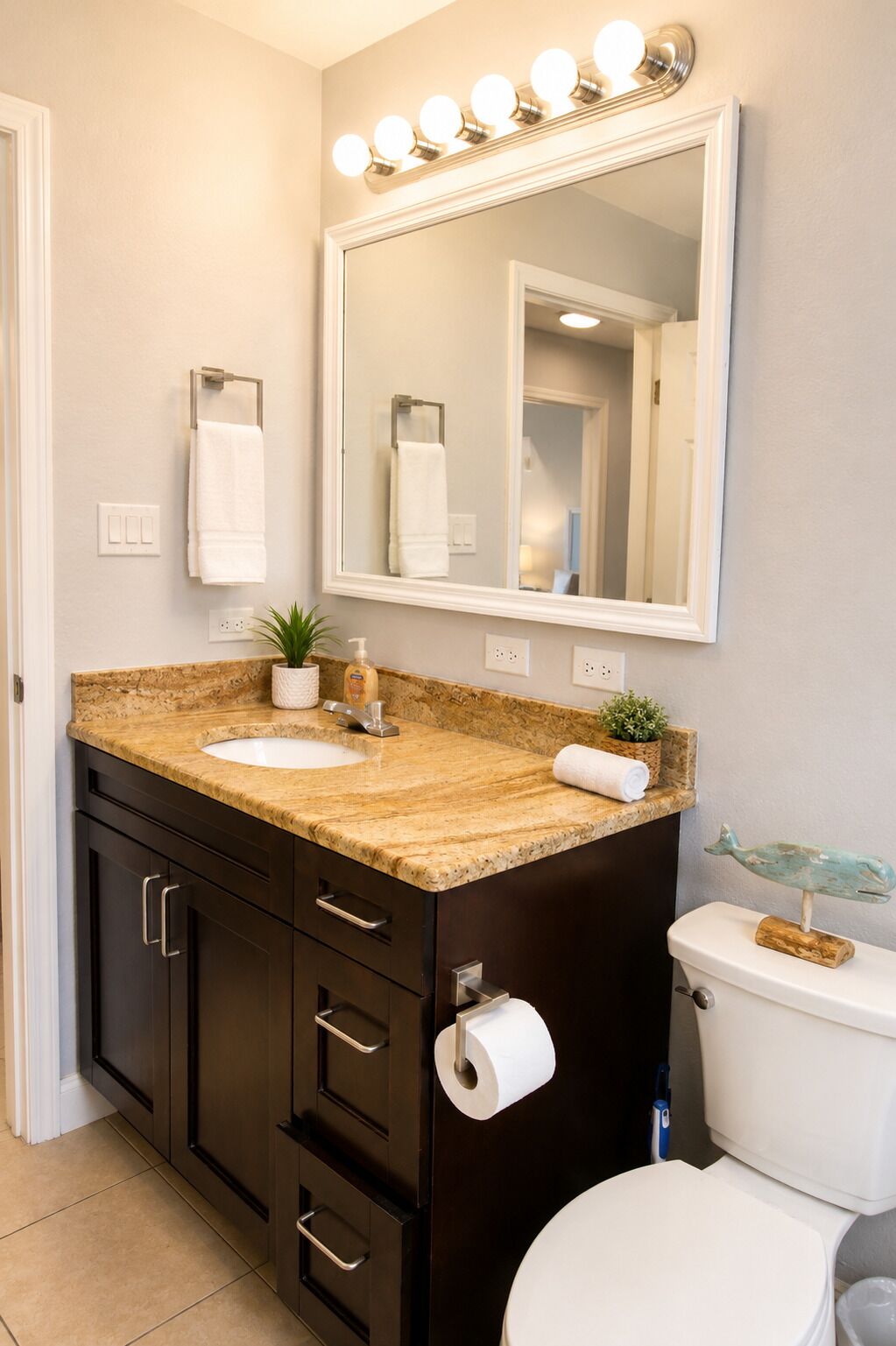 A bathroom with a vanity, sink, mirror, and toilet.