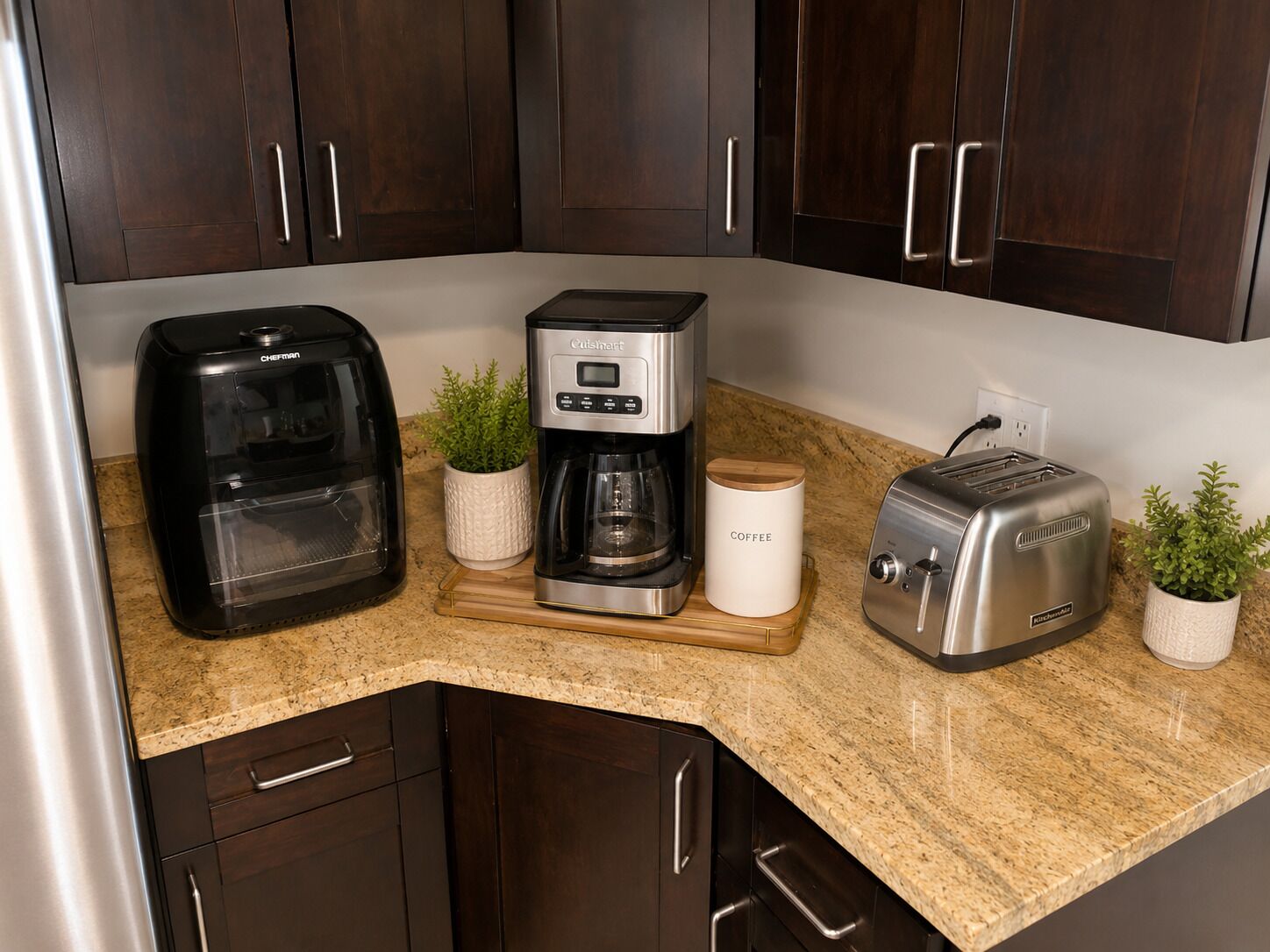 A kitchen with dark wooden cabinets, a coffee maker, a toaster, and a food processor.