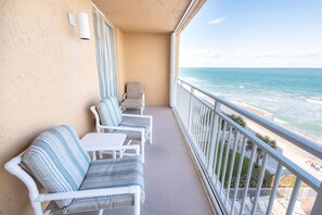 A balcony with white wicker furniture, a white table, and a view of the ocean. - Oceanfront 2BR Condo 6th Floor Corner Unit Indian Harbour Beach, 601 (Indian Harbour Beach)