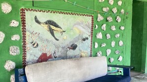 Un banco azul con cojín frente a una pared verde con un mural.