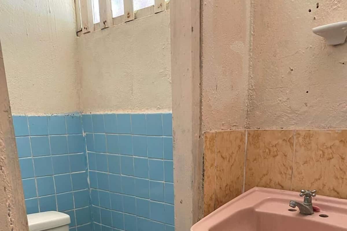 Um banheiro pequeno com vaso sanitário, pia e paredes com azulejos azuis e bege.