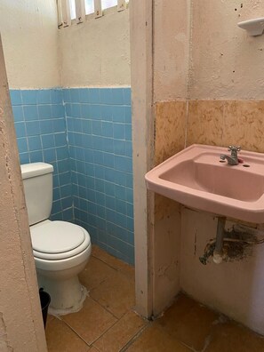 A small bathroom with a toilet, a sink, and blue and beige tiled walls. - Hotel El Porvenir (Narganá)