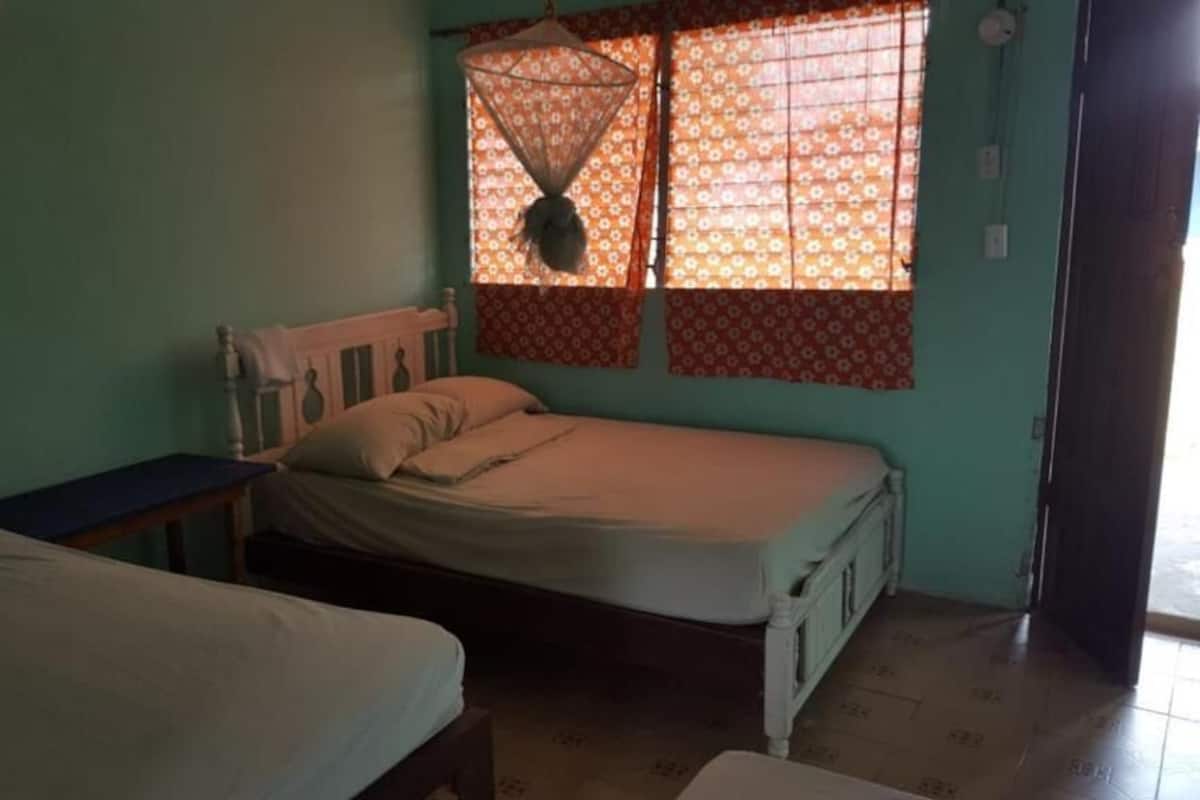 Um quarto com uma cama, uma mesinha e uma janela com cortinas estampadas.