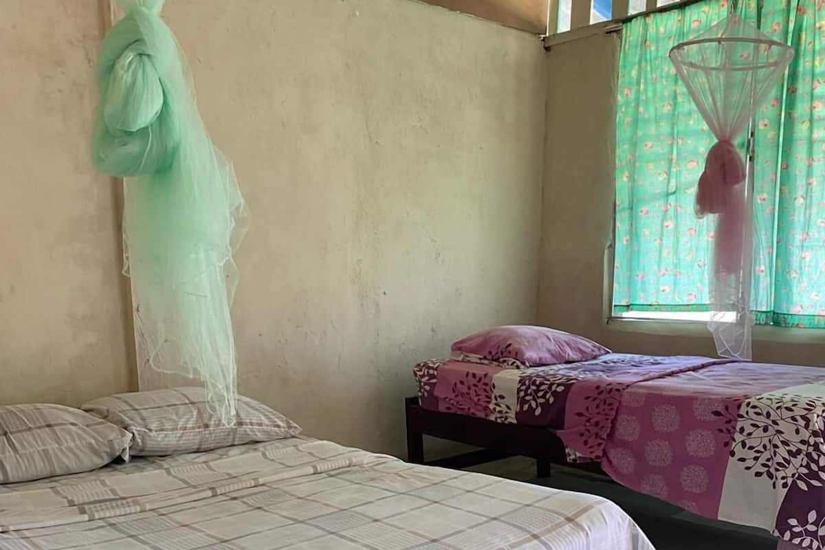 Quarto com uma cama, uma mesa pequena e uma janela com cortinas.