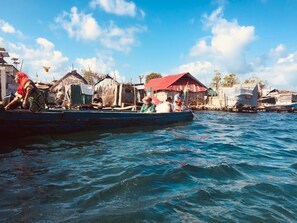 A boat with people on it, docked near a waterfront with buildings in the background. - Hotel El Porvenir (Narganá)