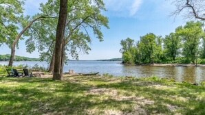 A lakeside camping area with a grassy area, a few trees, and a view of the lake. - Mighty Mississippi River Retreat (Scott County)