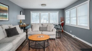 A living room with a grey sofa, a round coffee table, and a telescope. - Mighty Mississippi River Retreat (Scott County)