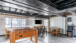 A room with a foosball table, bar area, and arcade games. - Mighty Mississippi River Retreat (Scott County)