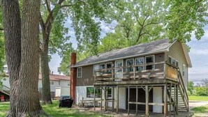 A two-story wooden house with a balcony, surrounded by trees. - Mighty Mississippi River Retreat (Scott County)