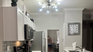 Una cocina moderna con armarios blancos, electrodomésticos de acero inoxidable y una isla central.