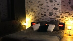 Ein Schlafzimmer mit einem Bett, zwei Nachttischlampen und einer Wand mit Steinoptik.