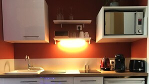 Eine kleine Küche mit Mikrowelle, Kaffeemaschine und Spüle.