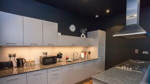 A modern kitchen with grey cabinets, a microwave, a kettle, and a gas stove.