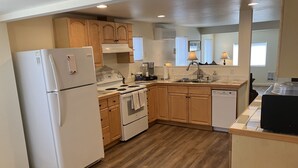Une cuisine de taille réduite, avec des meubles en bois, un réfrigérateur blanc, une cuisinière et un lave-vaisselle.