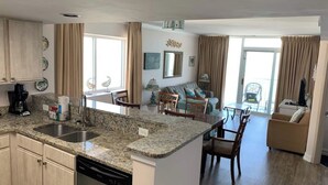 Una cocina moderna con encimeras de granito, lavavajillas y un comedor con mesa y sillas.