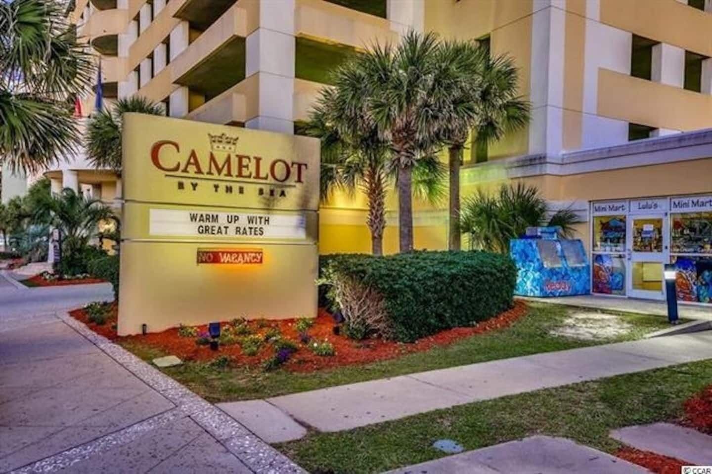 Et hotelskilt med navnet "Camelot by the Sea" og en besked om gode priser og ingen ledige værelser.
