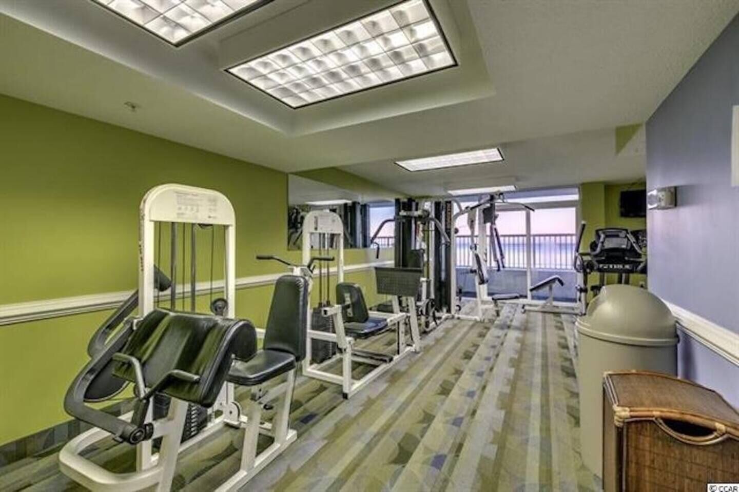 Une salle de sport équipée de matériel d’exercice, d’un tapis de course et d’une grande fenêtre offrant une belle vue.