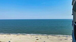 A beach view from a building with a clear sky and calm sea.