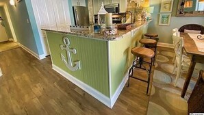 A kitchen with a central island, bar stools, and a dining table.