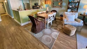 A spacious living room with a dining area, a kitchen with a central island, and a cozy seating area with a sofa and armchair.