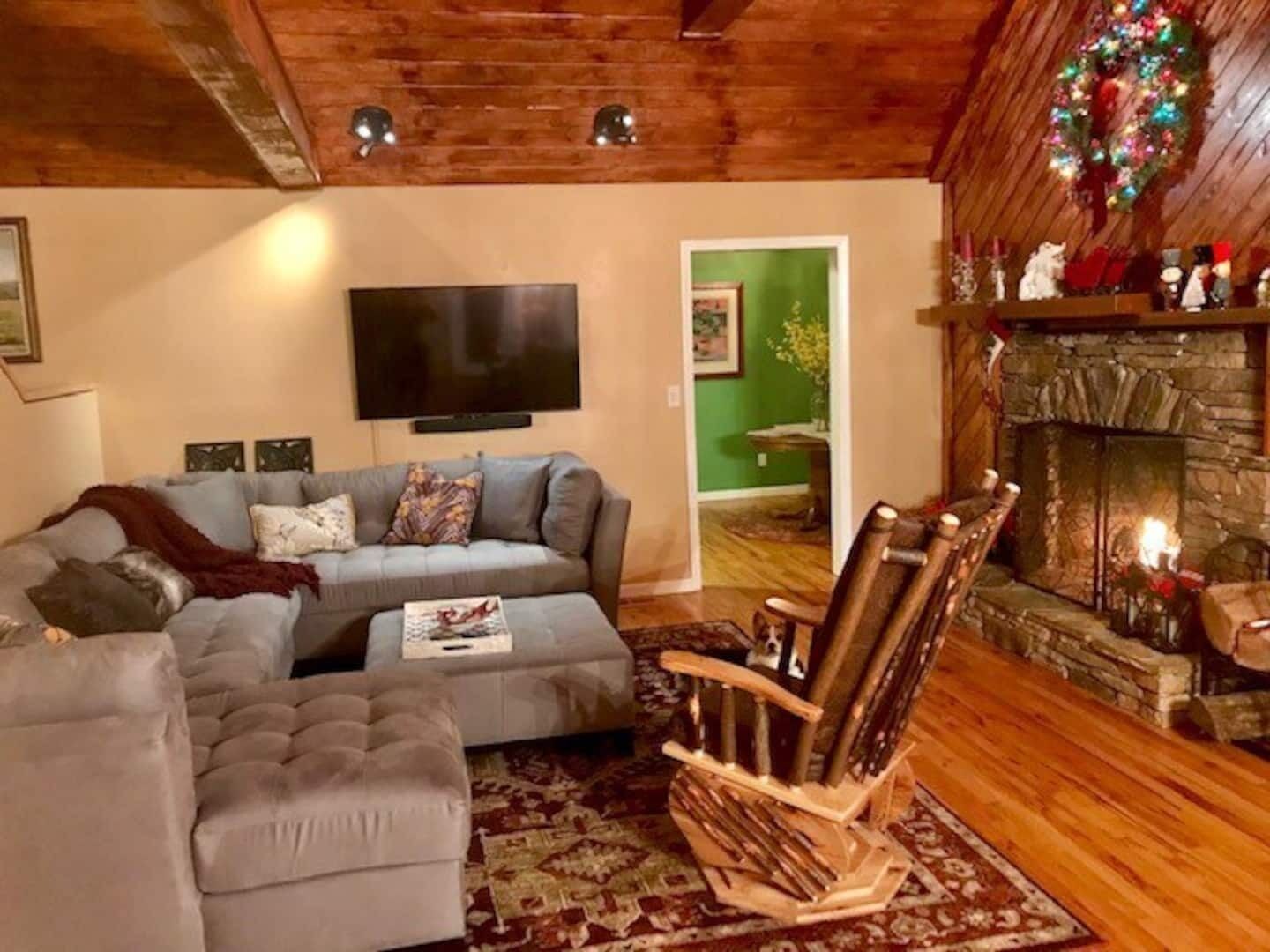 Ein gemütliches Wohnzimmer mit einem Ecksofa, einem Schaukelstuhl und einem Kamin.
