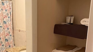 A bathroom with a sink, dark cabinets, a shower curtain, and a towel rack with folded towels. - Close to Beach and Fish Fry (Nassau)
