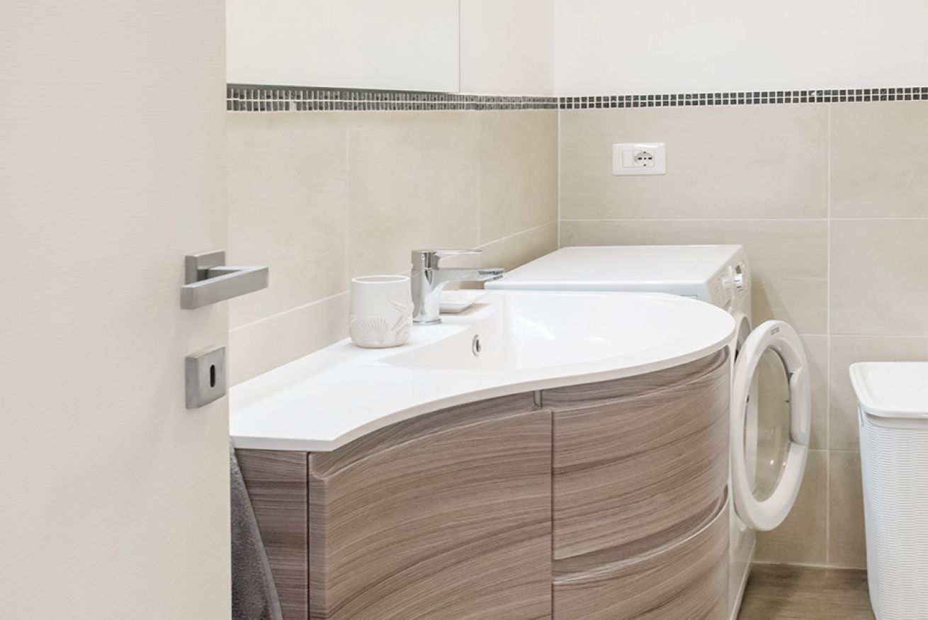 Une salle de bain moderne avec un meuble-lavabo aux lignes courbes, un lave-linge et des toilettes.
