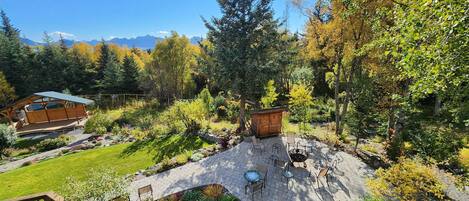 Un espace extérieur aménagé avec des meubles de jardin, une terrasse en bois et un chemin de pierre menant à un belvédère.