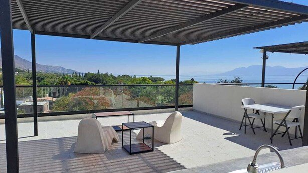 Une terrasse sur le toit offrant une vue sur la mer, un espace salon couvert et un bar.