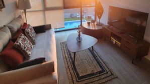 Un salon moderne avec un canapé, un téléviseur et de grandes fenêtres.